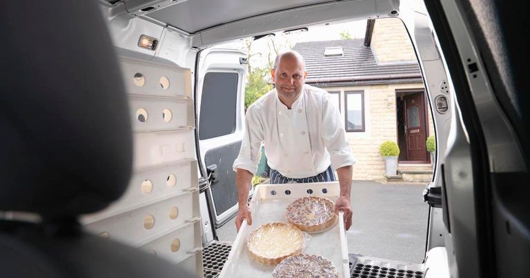 Baker loading pies into a van, with house visible in the background.
