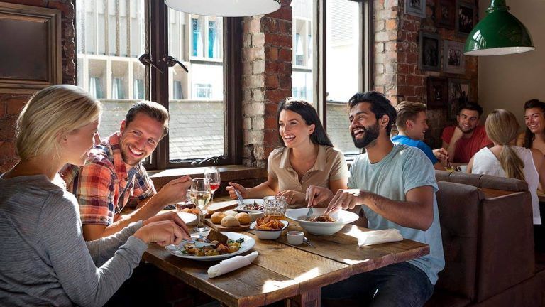 Restaurant customers enjoying a meal together at a table, smiling and talking in a warm, inviting atmosphere.