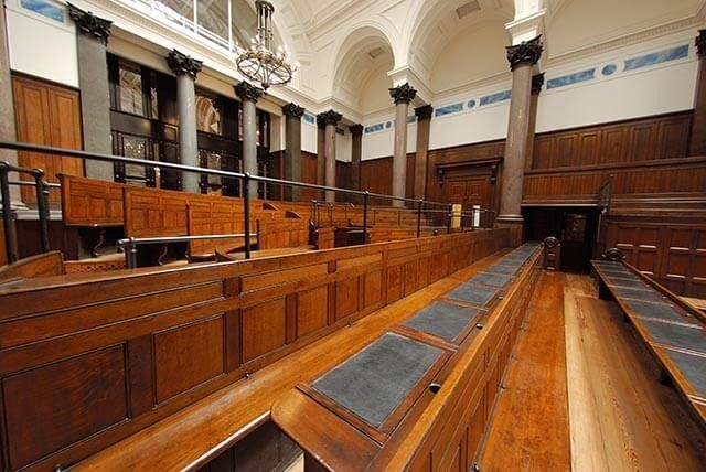 Older man in glasses checking documents at a table, with a woman next to him reviewing papers.