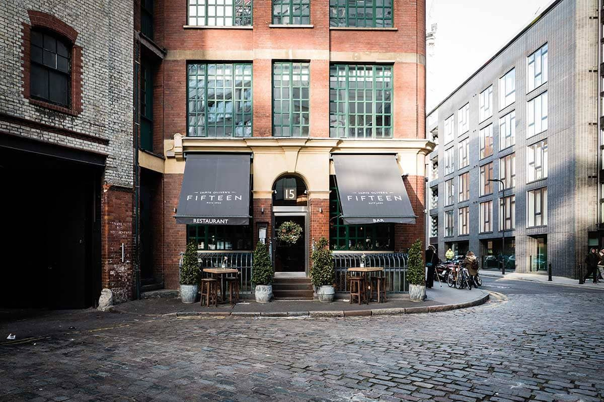 A brick building featuring a restaurant located at the corner, showcasing its inviting entrance and outdoor seating area.