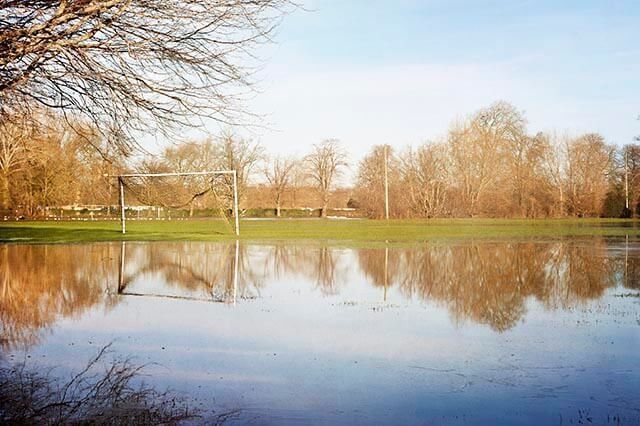 A flooded football pitch with standing water covering the grass.