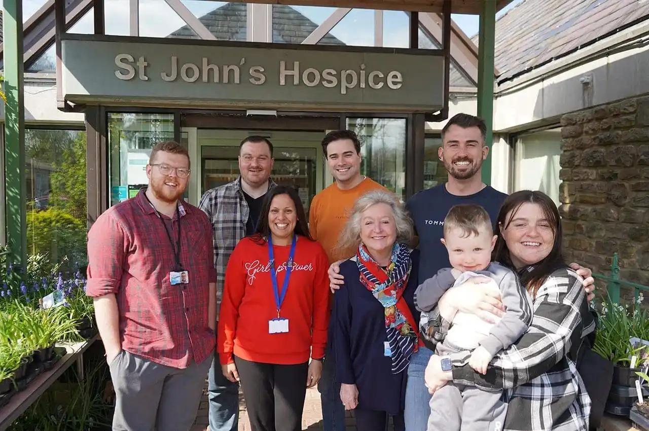 Some of the Premierline team stand together in front of St. John's Hospice, smiling.