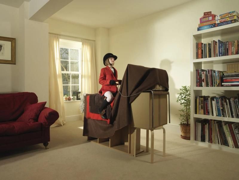 A child sat on an imaginary horse made out of furniture