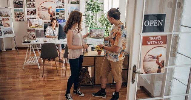 Two customers looking at a brochure in a travel office with a travel agent.
