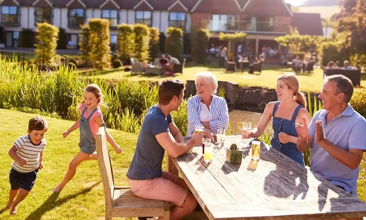 A family gathered around a table in a garden restaurant, enjoying a meal together and sharing smiles