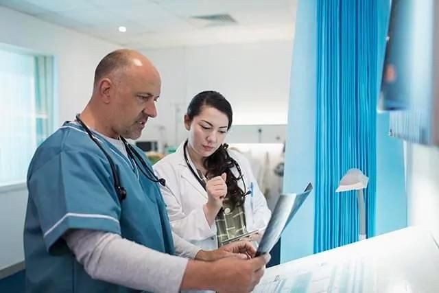 A male doctor and a female doctor are examining X-ray images in a medical setting.