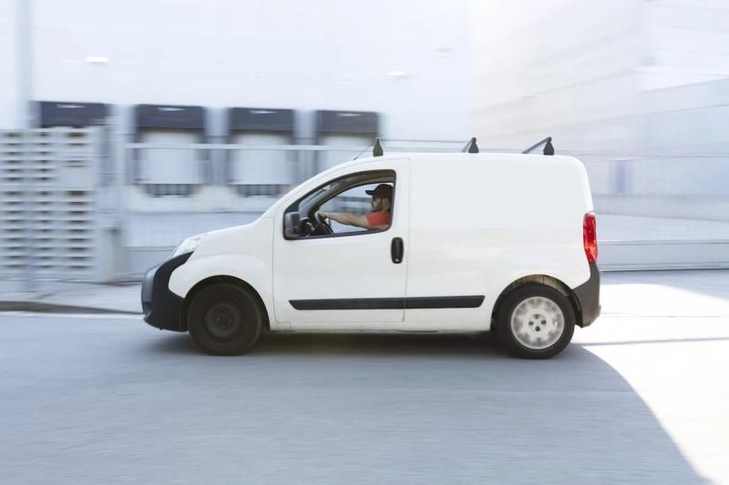 White van driving through a city