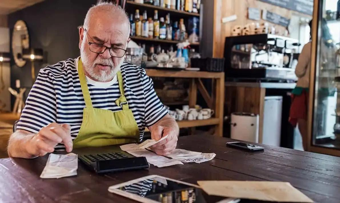 Person in sat at a table in a restaurant using a calculator