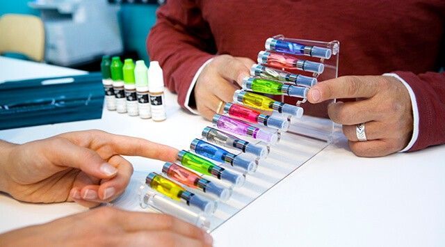 Two people examining colorful vape cartridges in a vape store.
