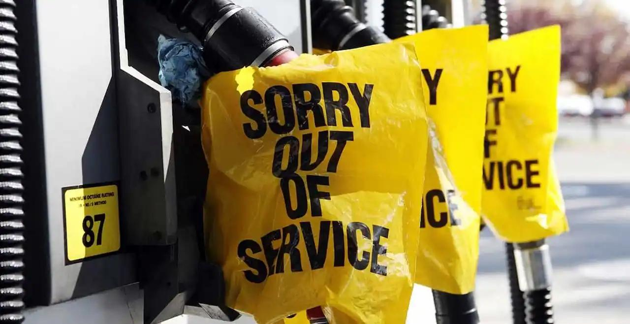 A fuel pump with yellow bags attached, displaying "Sorry, out of service" messages.