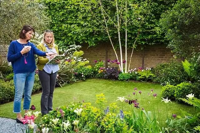 A gardener in a garden is discussing garden arrangements with the client.